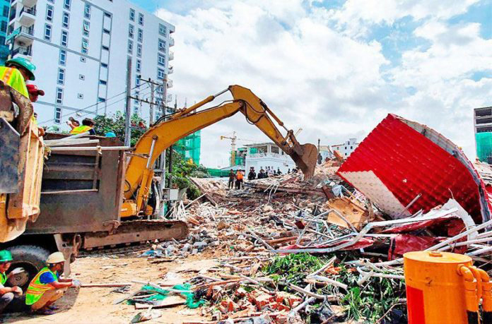 Rescue workers use an earthmover to clear debris after an under-construction building collapsed in Sihanoukville on June 22, 2019.